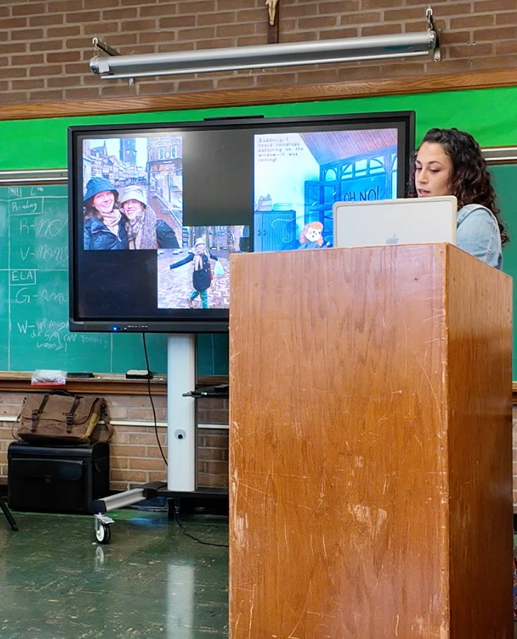 Chelsea presenting from a podium with book illustrations on screen