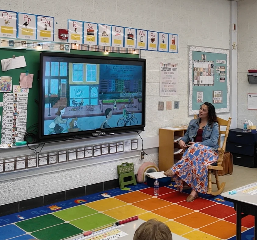 Chelsea reading 'My Amsterdam Day' to young students